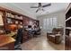 Comfortable home office with custom built-ins, desk, chair, ceiling fan, and a leather recliner at 16444 W Chuparosa Ln, Surprise, AZ 85387