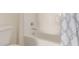 Bright white bathtub and shower featuring neutral patterned curtain and chrome fixtures at 23126 N 45Th Pl, Phoenix, AZ 85050