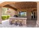 A cozy covered patio offers seating at the bar, an outdoor kitchen, and outdoor lighting at 23126 N 45Th Pl, Phoenix, AZ 85050