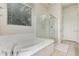 Bright bathroom featuring a soaking tub, glass-enclosed shower, and large window at 27105 W Marco Polo Rd, Buckeye, AZ 85396