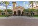Impressive clubhouse exterior with arched entrance, palm trees, and manicured landscaping at 27105 W Marco Polo Rd, Buckeye, AZ 85396