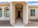 Covered front porch with gated front door, arched windows and desert landscaping at 27105 W Marco Polo Rd, Buckeye, AZ 85396
