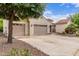 Spacious driveway leading to a three-car garage with neutral doors and desert landscaping at 27105 W Marco Polo Rd, Buckeye, AZ 85396