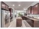 Gourmet kitchen featuring stainless steel appliances, dark wood cabinets, and a kitchen island at 27105 W Marco Polo Rd, Buckeye, AZ 85396