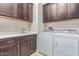 Laundry room with a utility sink, dark wood cabinets, and a washer and dryer at 27105 W Marco Polo Rd, Buckeye, AZ 85396