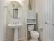 Charming powder room featuring pedestal sink, toilet with storage cabinet, and neutral decor at 27105 W Marco Polo Rd, Buckeye, AZ 85396