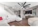 Bright living room featuring a sleek ceiling fan, a television, and a white sofa, with a staircase on the side at 4135 E Waterman Ct, Gilbert, AZ 85297