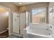 Inviting bathroom with shower, tub, and view to outdoors through the window at 41413 W James Ln, Maricopa, AZ 85138