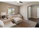 Cozy living room with a white sectional, chair, and neutral carpet with view to outdoors at 41413 W James Ln, Maricopa, AZ 85138