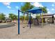 Community playground with climbing structure, swings, covered tables, and sand at 41413 W James Ln, Maricopa, AZ 85138