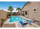 Relaxing backyard pool, featuring a waterfall feature, blue lounge chairs, and lush landscaping at 41413 W James Ln, Maricopa, AZ 85138
