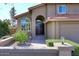 Inviting front entrance with an arched doorway, large windows, and a meticulously landscaped garden pathway at 5879 E Marconi Ave, Scottsdale, AZ 85254