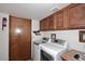 Laundry room featuring washer, dryer, wooden cabinets, utility sink, and door at 5879 E Marconi Ave, Scottsdale, AZ 85254
