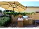 Outdoor kitchen featuring a stainless steel BBQ and a tiled counter, shaded by a large umbrella at 5879 E Marconi Ave, Scottsdale, AZ 85254