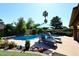 Enjoy this serene pool, framed by mature trees and landscaped beds, complete with patio chairs at 5879 E Marconi Ave, Scottsdale, AZ 85254
