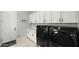Functional laundry room featuring black washer and dryer, and white cabinets at 8149 E Jaeger St, Mesa, AZ 85207
