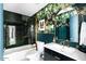 Modern bathroom with black tiled shower, vanity with gold hardware, and botanical wallpaper at 8734 E Amelia Ave, Scottsdale, AZ 85251