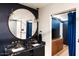 Modern bathroom with double sinks, black marble countertops, and a round mirror at 8734 E Amelia Ave, Scottsdale, AZ 85251