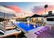 Stunning backyard pool with lounge chairs, umbrellas, bar seating, and a serene waterfall feature, ideal for relaxation at 8734 E Amelia Ave, Scottsdale, AZ 85251