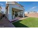 Expansive backyard featuring a covered patio, lush artificial grass, and a brick-lined walkway at 10035 E Trent Ave, Mesa, AZ 85212