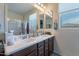 Bright bathroom featuring double sinks, a vanity with wood cabinets and a large mirror at 10035 E Trent Ave, Mesa, AZ 85212