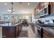 Spacious kitchen boasts a center island, stainless steel appliances, dark wood cabinets and granite countertops at 10035 E Trent Ave, Mesa, AZ 85212