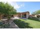 Beautiful backyard with a covered patio, artificial turf, lush trees, and manicured landscaping at 10371 W Pontiac Dr, Peoria, AZ 85382