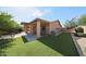 Spacious backyard featuring a covered patio, artificial grass, mature trees, and beautiful landscaping at 10371 W Pontiac Dr, Peoria, AZ 85382