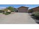 Tan single-story home featuring desert landscaping, two-car garage, and large concrete driveway at 10371 W Pontiac Dr, Peoria, AZ 85382
