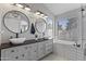 Modern bathroom featuring double vanity sinks, stylish lighting, and a separate tub and shower at 10733 W Clover Way, Avondale, AZ 85392