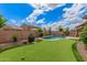 Lush backyard featuring a sparkling pool, well-manicured grass, and a fun putting green at 10741 W Paso Trl, Peoria, AZ 85383