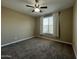 This bedroom has neutral colored walls and carpet with a ceiling fan and window at 10743 W Bronco Trl, Peoria, AZ 85383