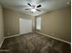 This bedroom has neutral colored walls and carpet with a ceiling fan and window at 10743 W Bronco Trl, Peoria, AZ 85383