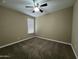 This bedroom has neutral colored walls and carpet with a ceiling fan and window at 10743 W Bronco Trl, Peoria, AZ 85383