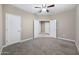 Neutral bedroom features carpeted floors, ceiling fan, and multiple doors at 10743 W Bronco Trl, Peoria, AZ 85383
