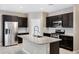 Modern kitchen featuring dark cabinets, granite countertops, stainless steel appliances and a center island at 10743 W Bronco Trl, Peoria, AZ 85383