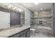 Bathroom featuring a sink, granite counters, and a glass-enclosed tub with decorative tile at 11342 E Laguna Azul Cir, Mesa, AZ 85209