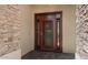 Elegant stone and stucco entryway with a custom-designed metal front door and tiled porch at 11342 E Laguna Azul Cir, Mesa, AZ 85209