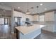 Bright kitchen boasts a large island, stainless steel appliances, white cabinetry, and wood-look tile floors at 11656 W Luxton Ln, Avondale, AZ 85323
