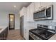 Modern kitchen with stainless appliances, gray backsplash, quartz countertops, and wood-look tile at 11656 W Luxton Ln, Avondale, AZ 85323