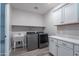 Well-lit laundry room features sleek gray washer and dryer, sink, and ample cabinet space at 11656 W Luxton Ln, Avondale, AZ 85323