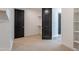 Walk-in closet with neutral carpet, black doors, and wood shelves and rods at 11656 W Luxton Ln, Avondale, AZ 85323
