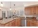 Well-lit kitchen with granite countertops, wood cabinets, stainless steel dishwasher, and plantation shutters, offering a functional and stylish space at 12686 N 95Th Way, Scottsdale, AZ 85260