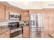 Kitchen featuring stainless steel appliances including refrigerator, microwave, and oven, complemented by granite countertops and wooden cabinets at 12686 N 95Th Way, Scottsdale, AZ 85260
