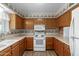 Traditional kitchen featuring wooden cabinets, white appliances, and patterned wallpaper at 131 N Higley Rd # 51, Mesa, AZ 85205