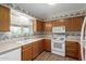 Traditional kitchen featuring wooden cabinets, white appliances, and patterned wallpaper at 131 N Higley Rd # 51, Mesa, AZ 85205