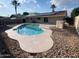An in-ground pool is surrounded by rock landscaping in this home's backyard with solar panels at 1545 W Marco Polo Rd, Phoenix, AZ 85027