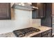 Close-up of a stovetop, white subway tile backsplash and dark wood cabinetry at 16679 W Saguaro Park Ln, Surprise, AZ 85387