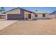 Charming single-story home featuring a gravel yard, gray garage door, and modern architecture under a clear sky at 17040 N 39Th Ave, Glendale, AZ 85308