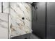 Updated shower showing contrasting black and marble tile, modern showerhead, and glass door at 17040 N 39Th Ave, Glendale, AZ 85308